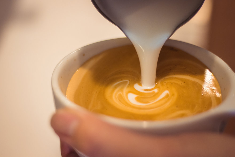 Milk being poured into coffee in a cup
